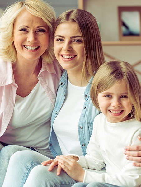 Mother and two daughters smiling after dental checkups