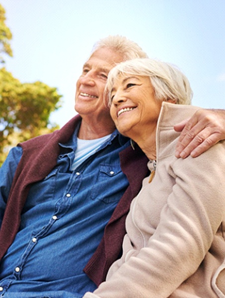 senior man and woman with a dental bridge in West Monroe sitting on a park bench