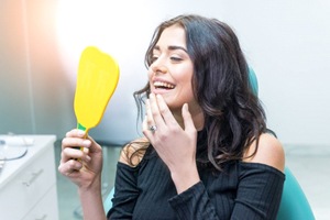 woman admiring her new dental bridge in a mirror