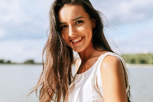 Woman with dental crowns in West Monroe, LA smiling by lake