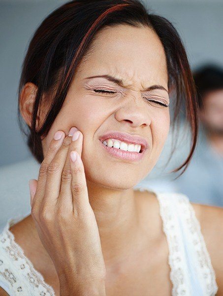 Woman holding jaw in pain before tooth extraction