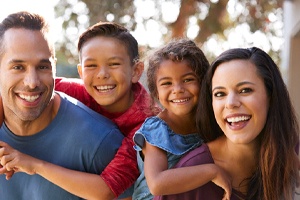 Parents holding kids on their backs while smiling outside