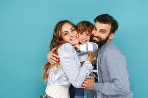Parents smiling with their kid while standing with blue background