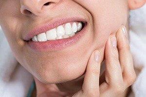Closeup of patient in pain from teeth grinding and clenching holding jaw