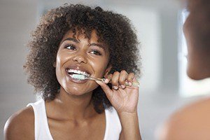 Woman brushing teeth to maintain good periodontal health