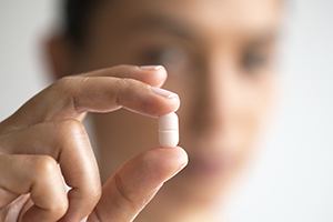 Hand holding white antibiotic gum disease therapy tablet