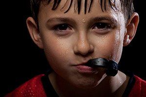 Young boy holding sportsguard in mouth