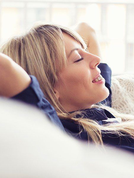 Relaxing woman with hands behind head after sedation dentistry visit