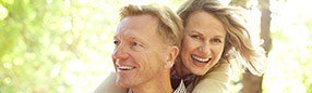 Smiling man and woman outdoors after restorative dentistry