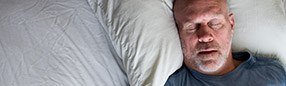 Man sleeping soundly in bed thanks to sleep apnea therapy