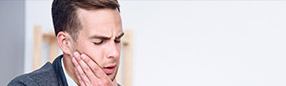 Man holding  jaw in pain before T M J therapy