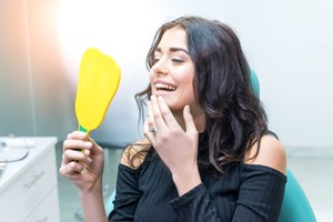 woman admiring her newly brightened smile in a mirror