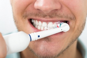 man brushing his teeth with an electric toothbrush