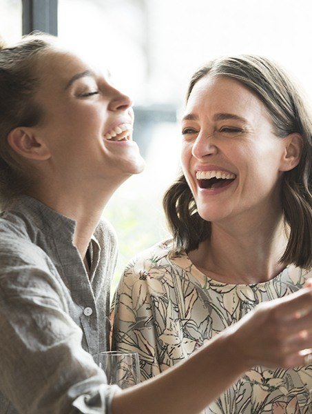Two laughing women with laughing after tooth colored filling restoration