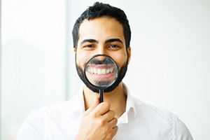 man holding a magnifying glass to his smile